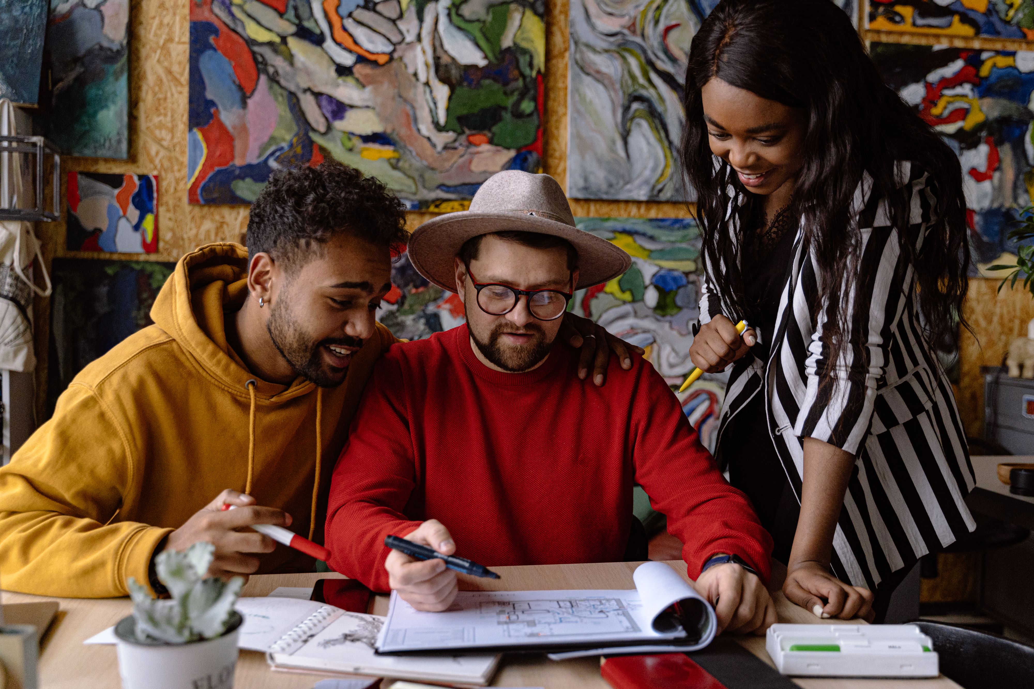 A diverse group discusses creative ideas at a desk in an art studio