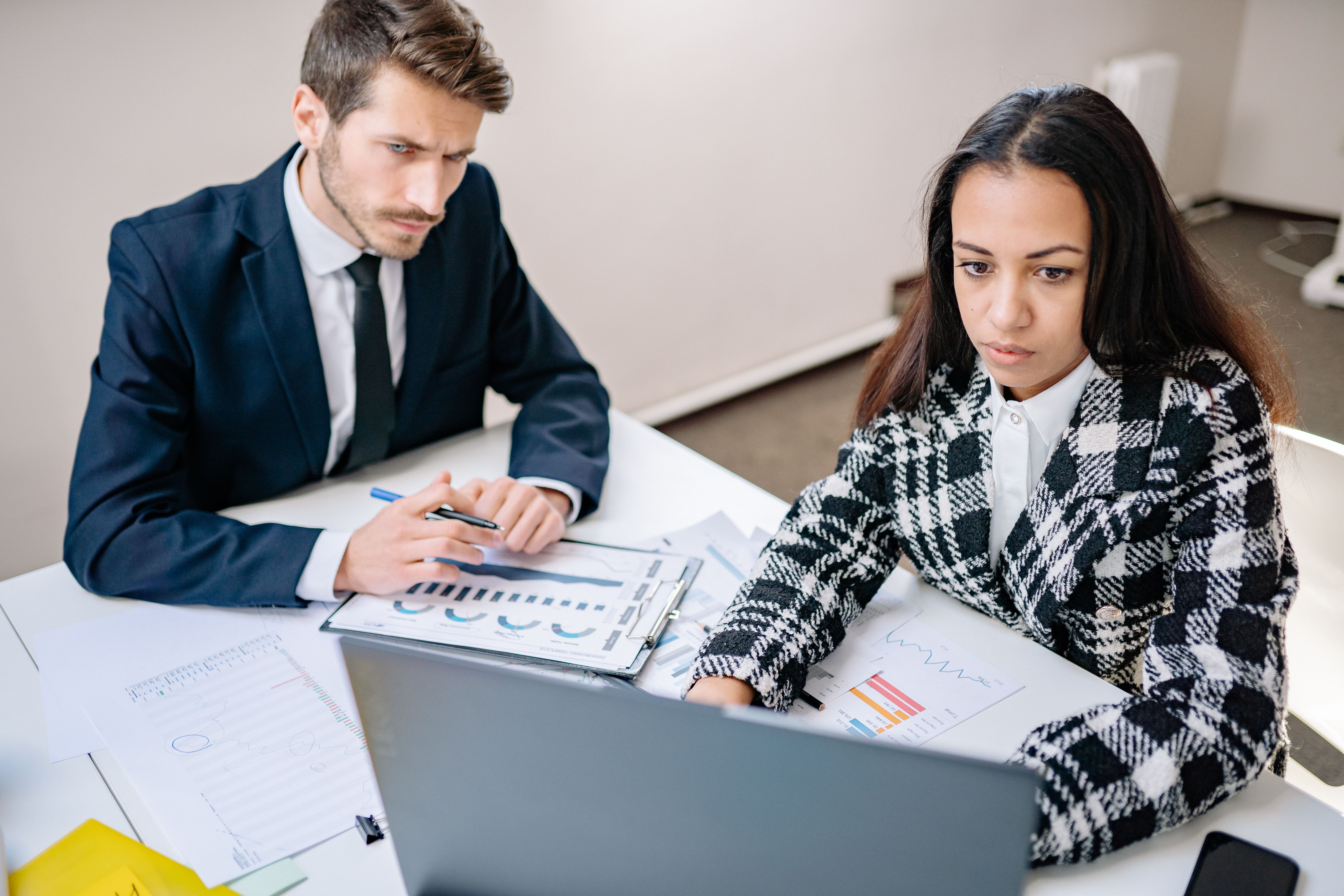 Two professionals collaborating on business analysis at a desk with charts